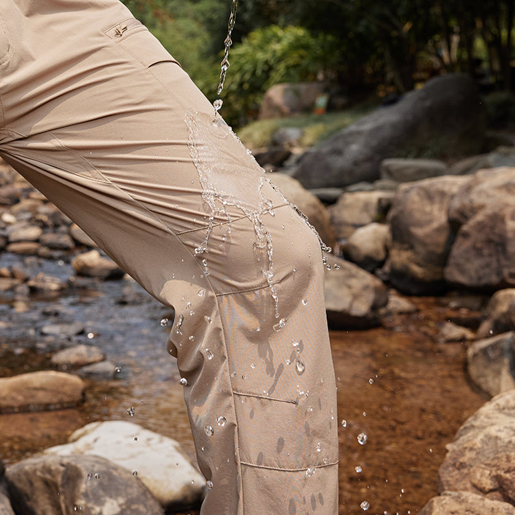 Water splashing off khaki water-resistant tactical pants by a rocky stream