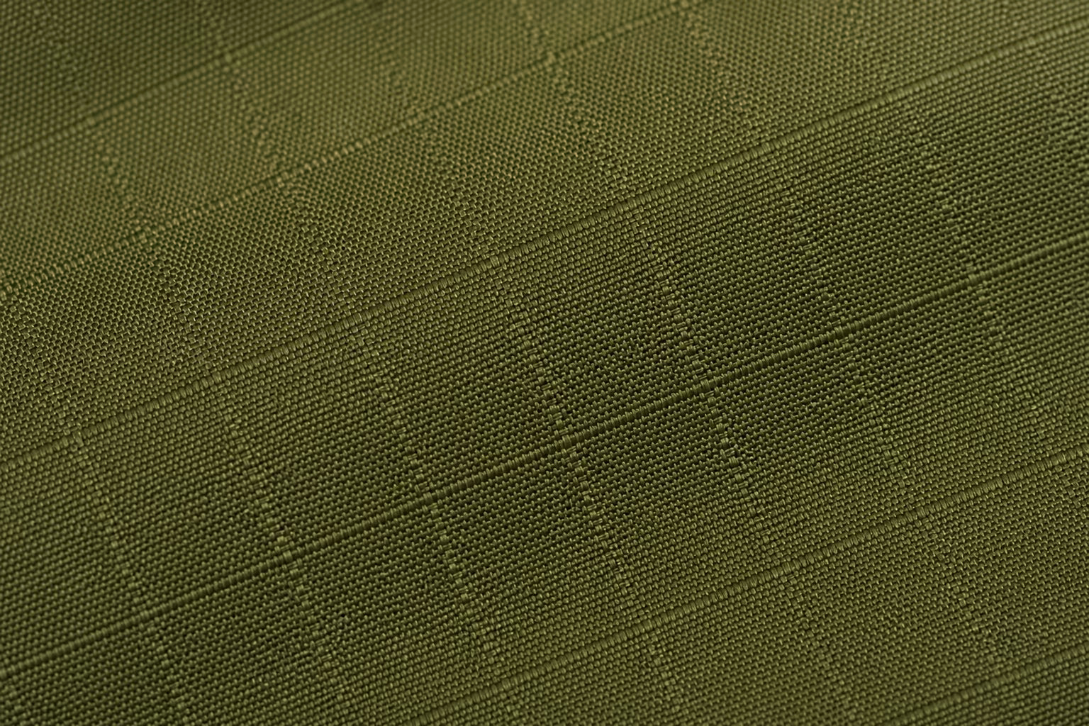 Macro close-up of olive green stretch ripstop fabric showing the visible crosshatch grid pattern with thicker reinforcement threads woven into a tighter base weave, studio lighting